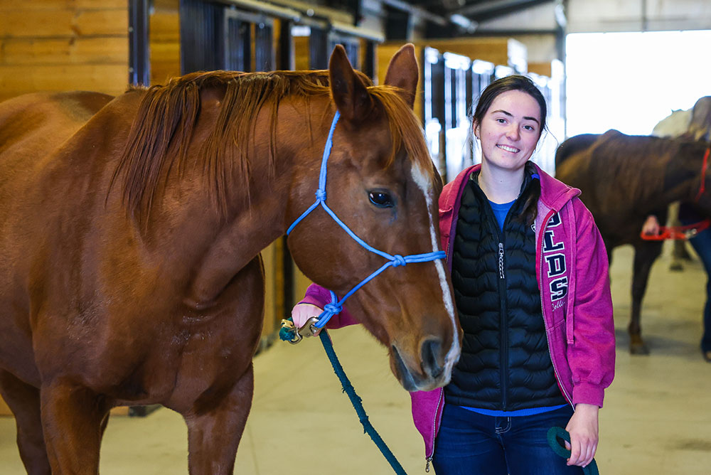 Student wearing an Olds College Vest standing with a horse.
