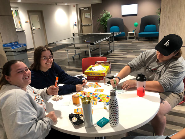 A group of students at a table smile at the camera.